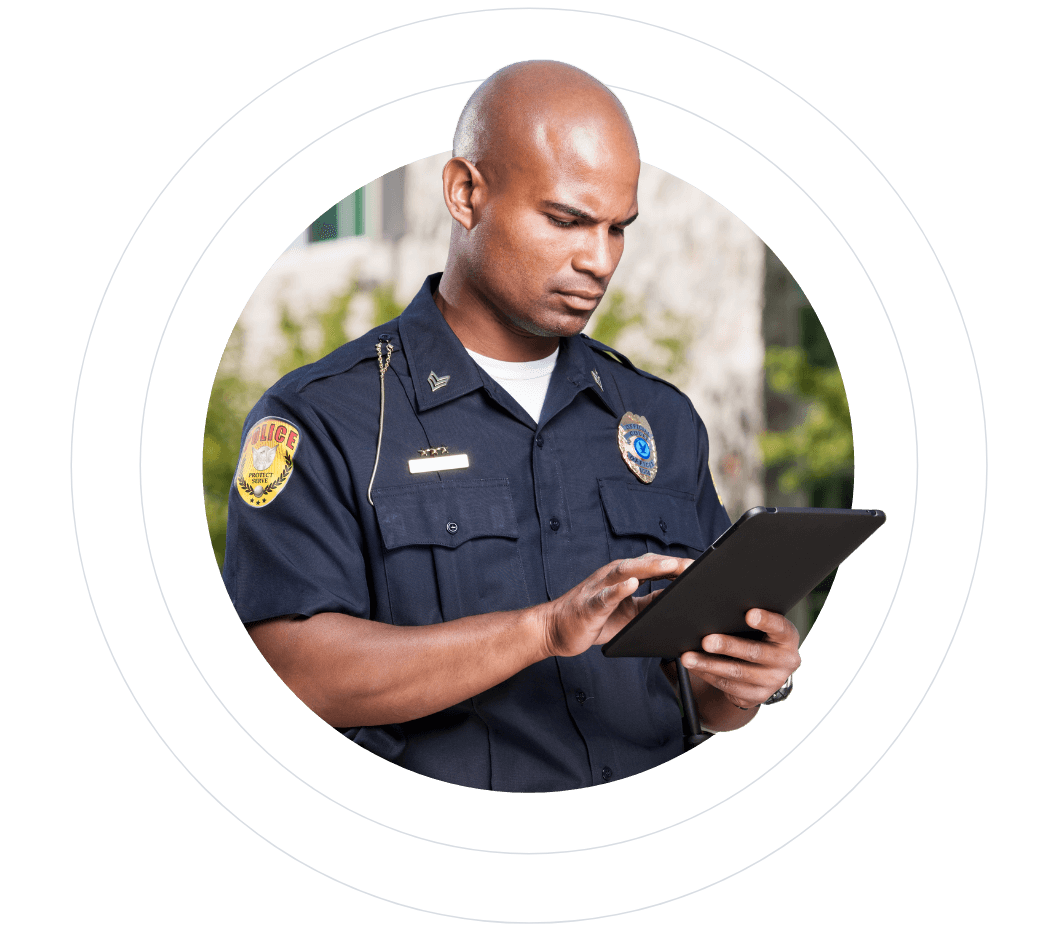 Police officer using a tablet, wearing a uniform with a focus on his badge.