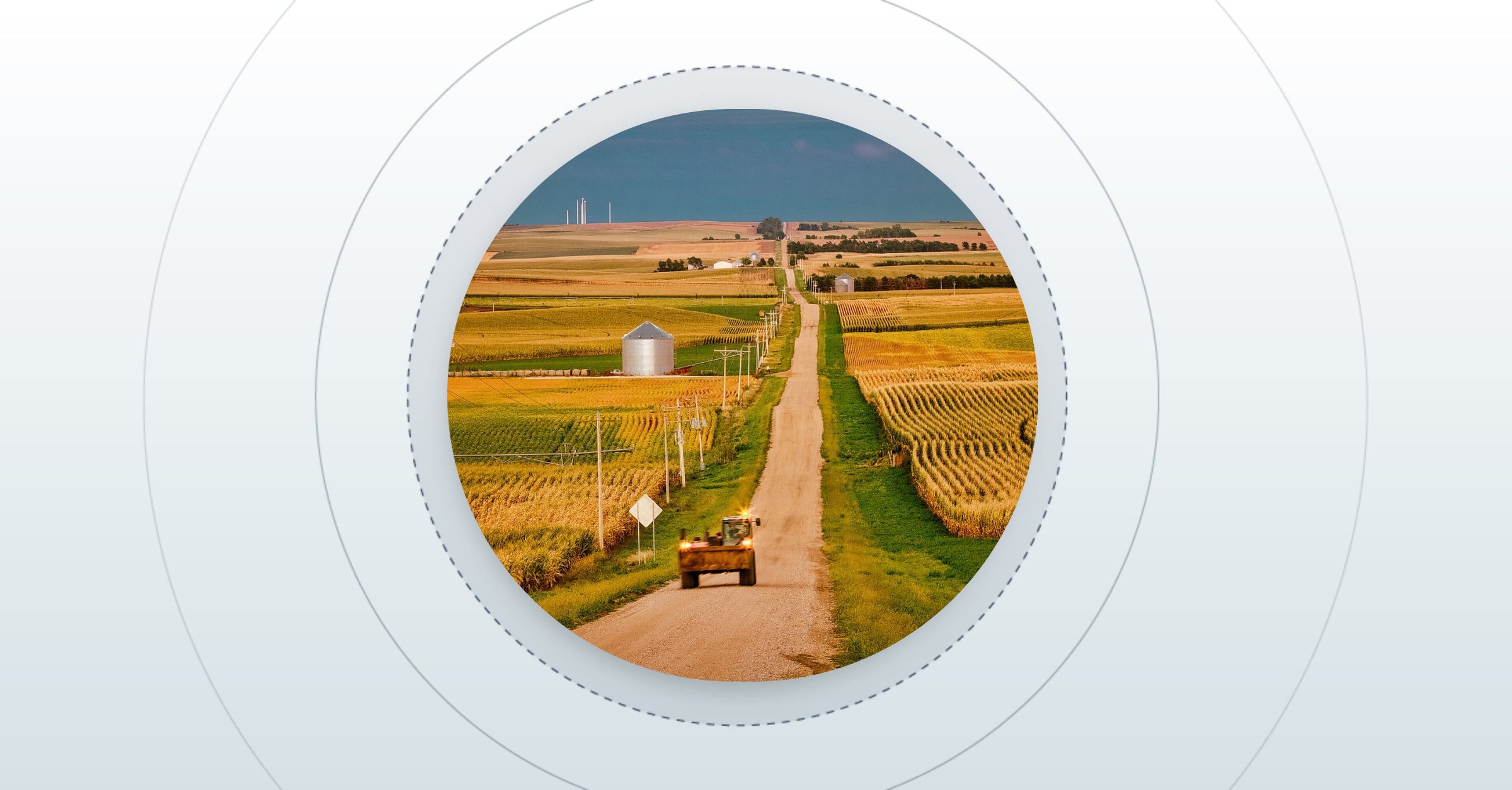 tractor driving down a dirt road with wheat fields on both sides