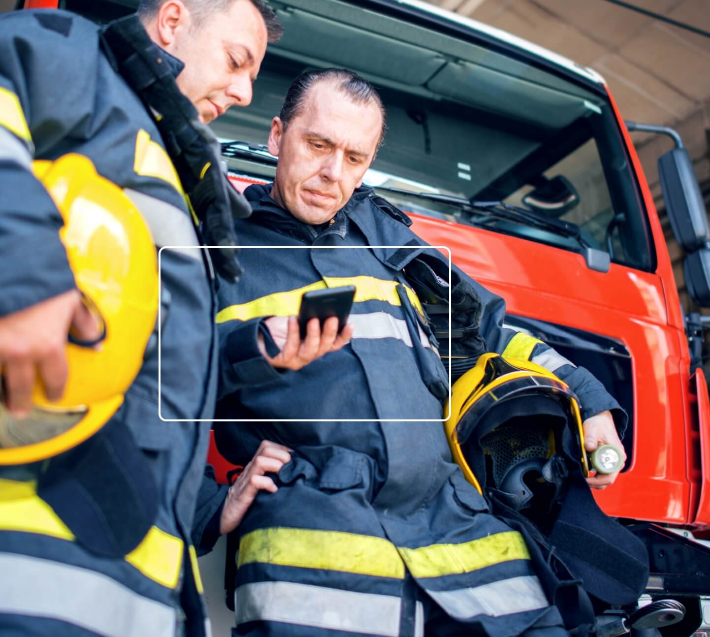 Two firemen looking at situation information on mobile smartphone