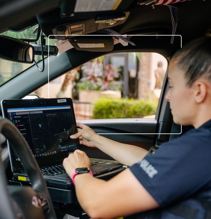 A police officer using her laptop in her patrol car