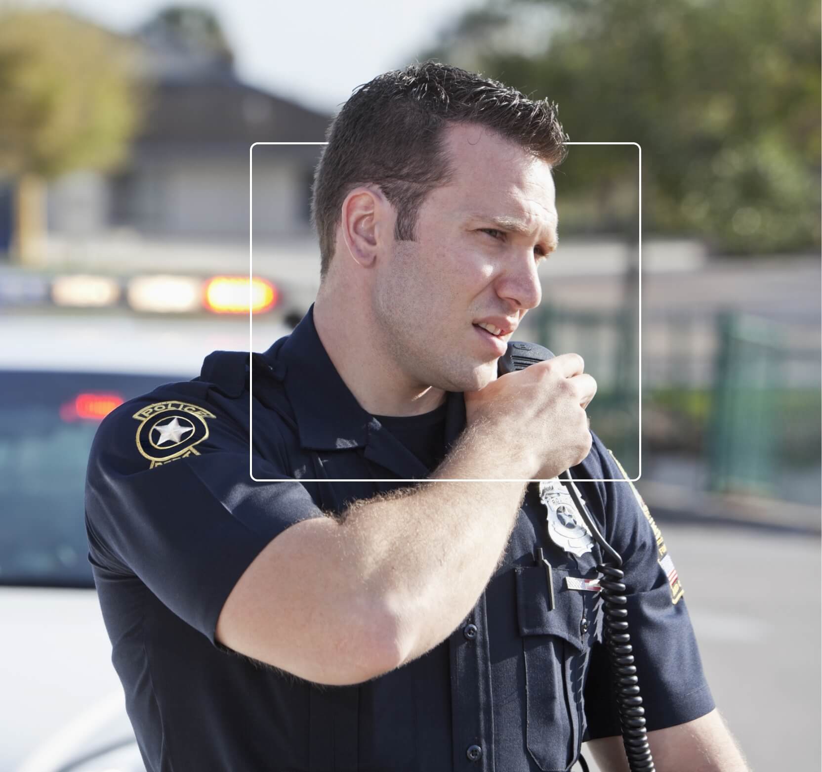 On-duty police officer looking into distance with serious expression while talking into radio