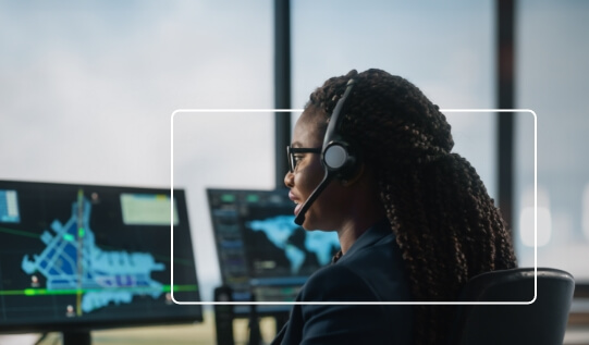 Female operator wearing a headset and monitoring data on multiple screens