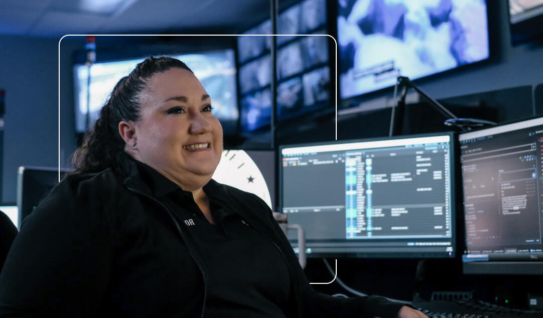 Female operator smiling and sitting by her computer screens