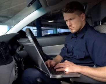 Police officer working on a laptop inside a patrol car