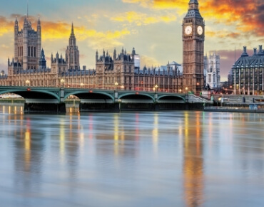 Scenic view of the Houses of Parliament and Big Ben in London, with a reflection on the River Thames at sunset.