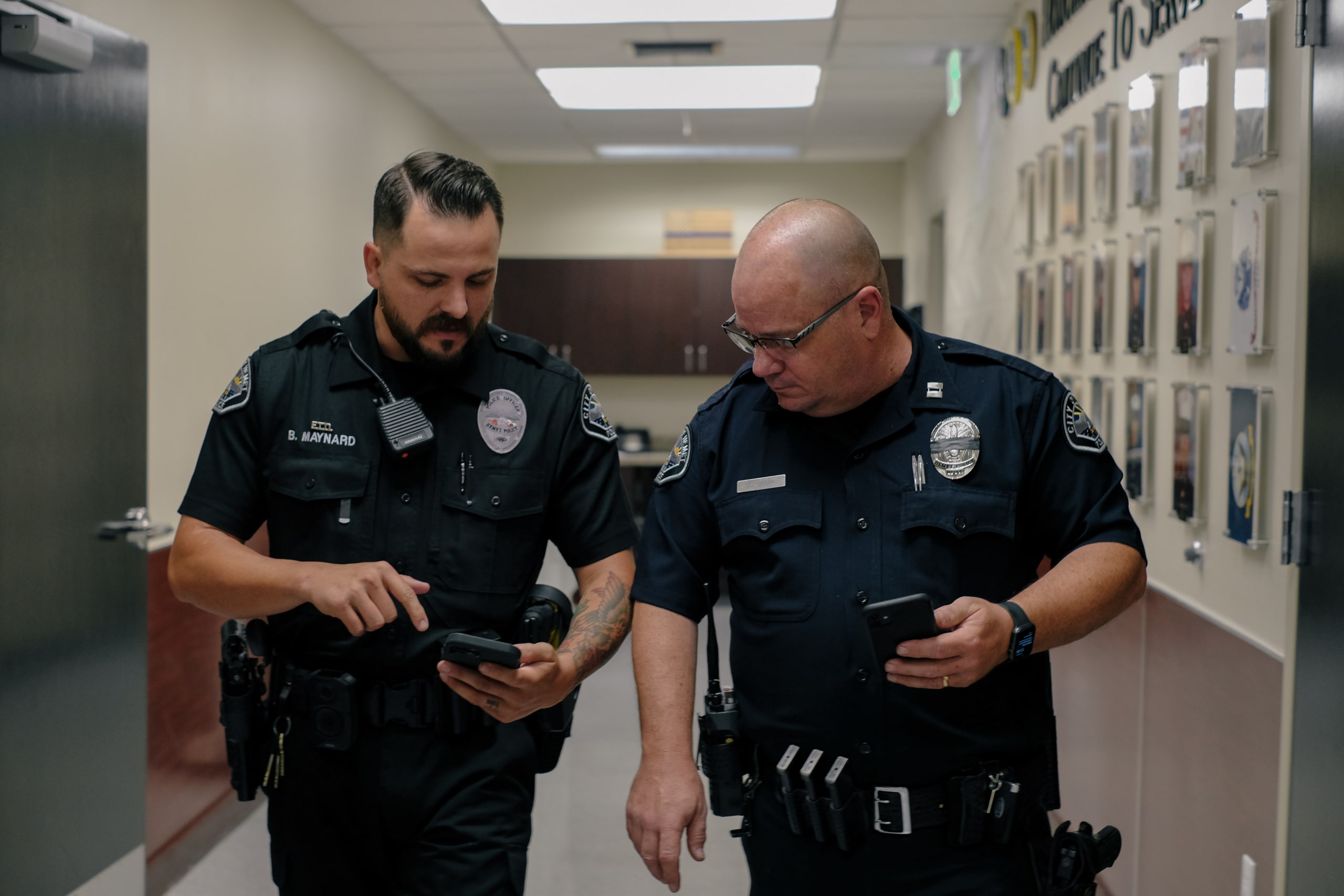 two police men talking and using smart phones